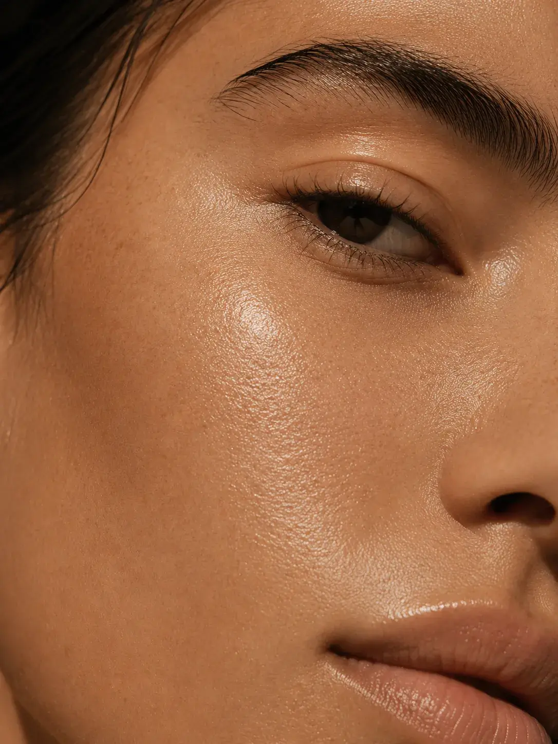 Gros plan demi-visage femme – peau parfaite bronzée lumineuse, texture peau, éclairage studio