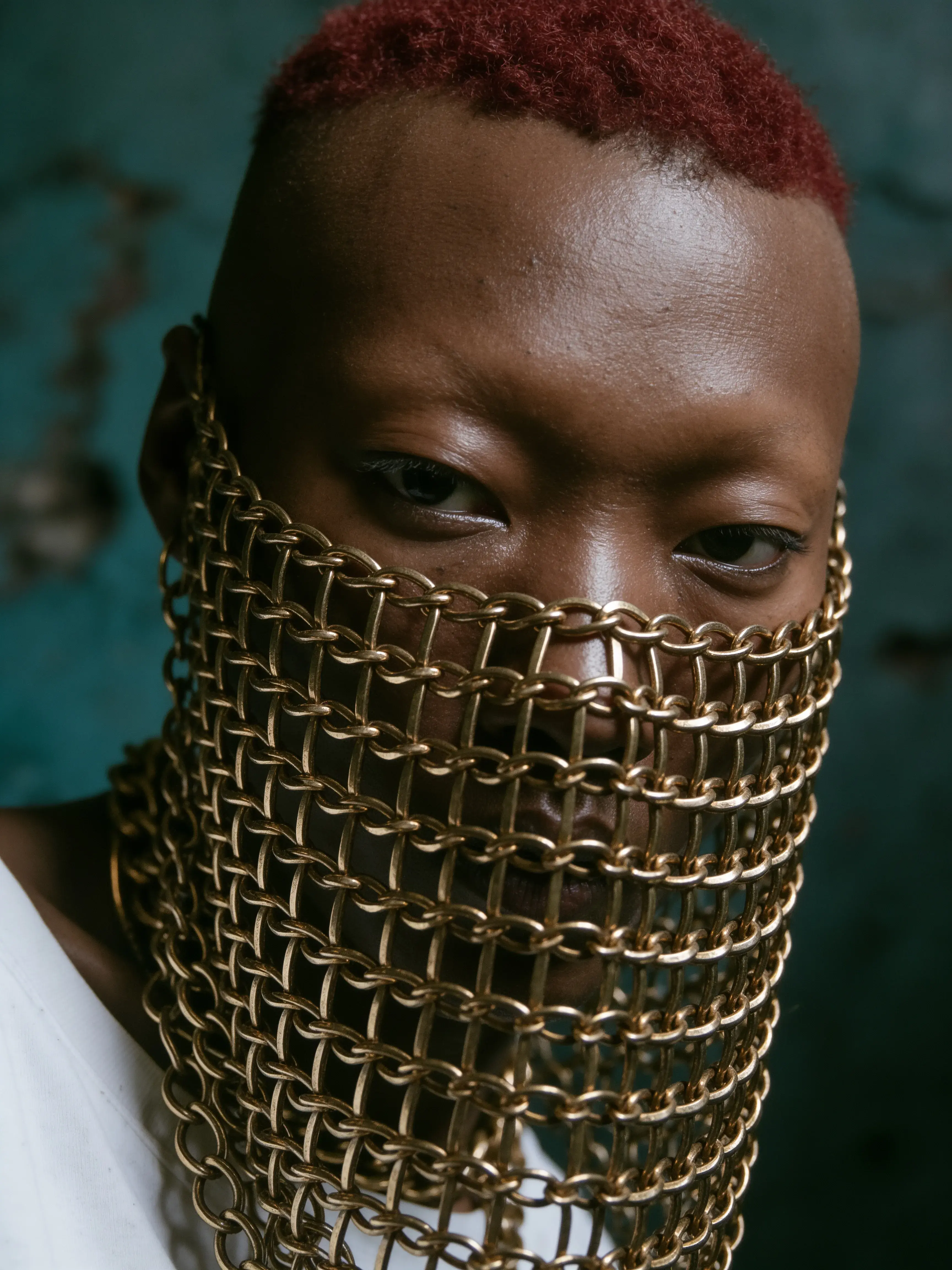 Gros plan du visage d'un homme noir caché derrière un voile de mailles de chaînes dorées