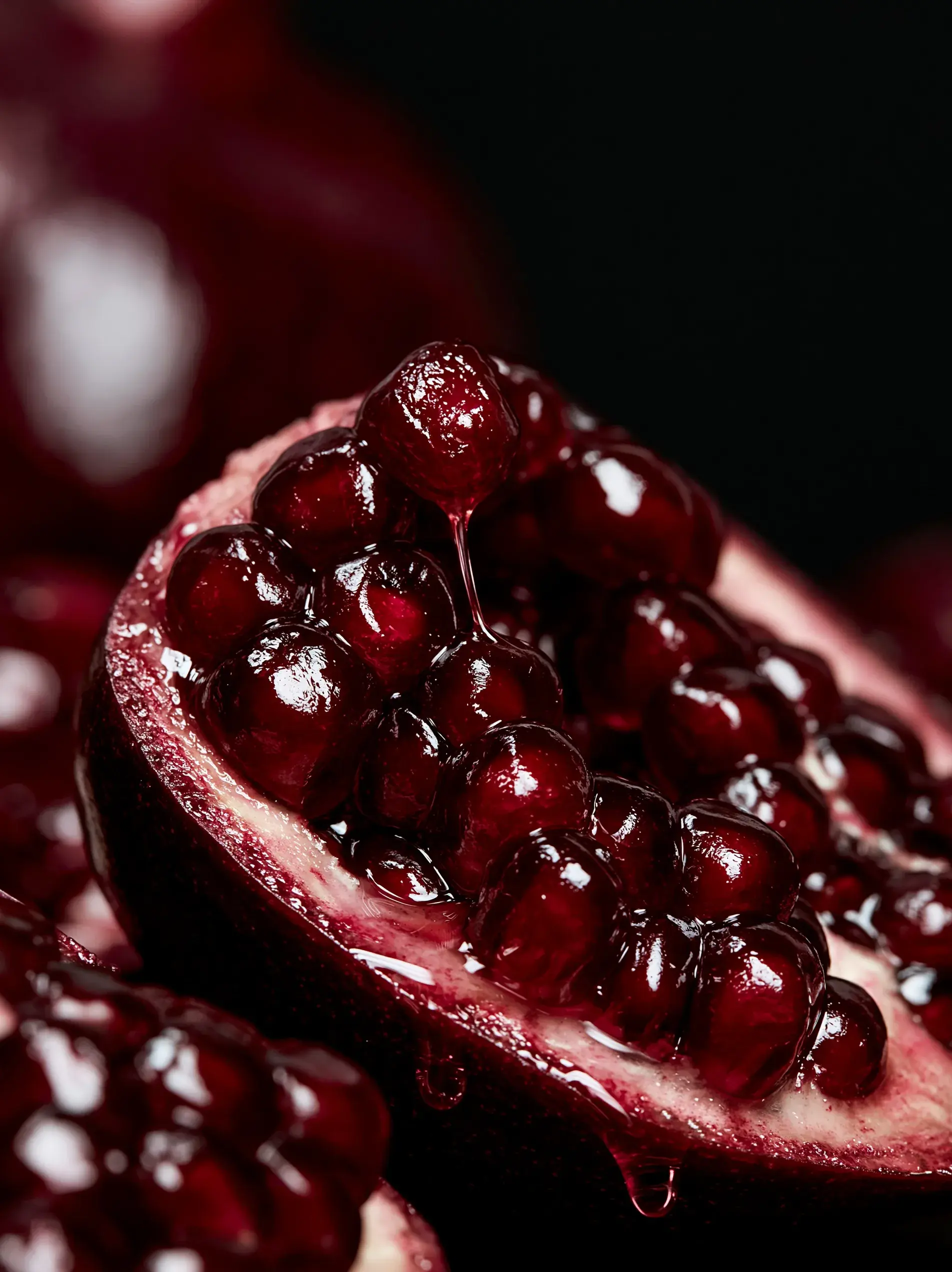 Gros plan macro sur des arilles de grenade rouge vif fond noir