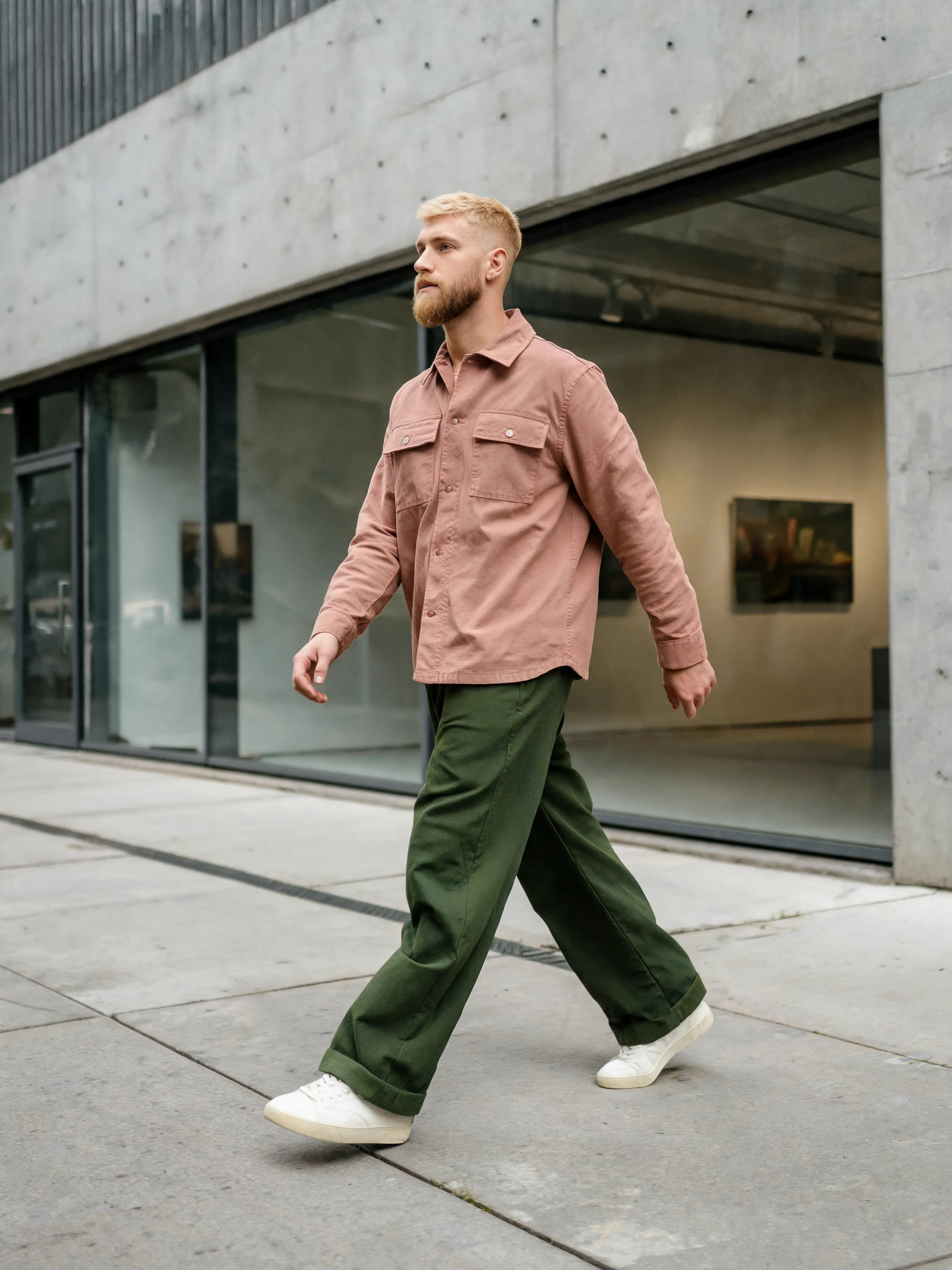 Homme chemise rose pantalon vert large marchant en ville – bâtiment béton contemporain, trottoir