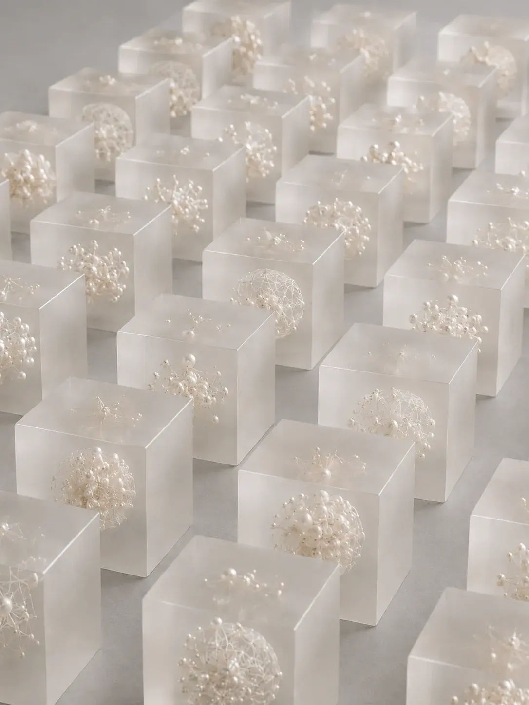 Installation sérielle de cubes translucides en résine renfermant des amas de perles