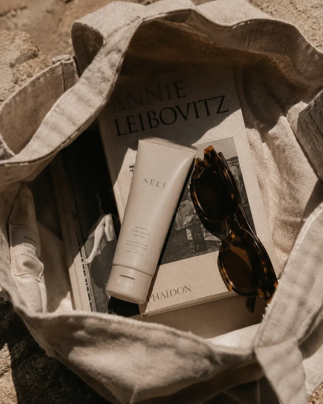 Intérieur tote bag lin – tube crème solaire, livres de photo, lunettes de soleil écaille, plein air