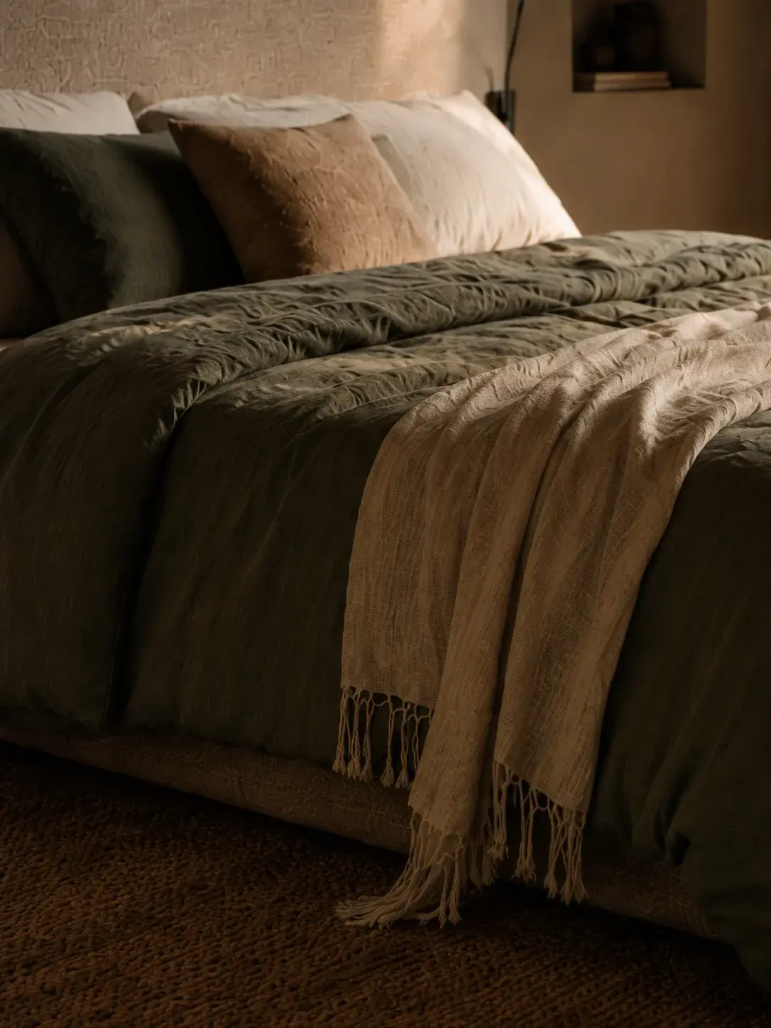 Lit avec draps en lin froissés aux tons naturels dans une chambre cosy