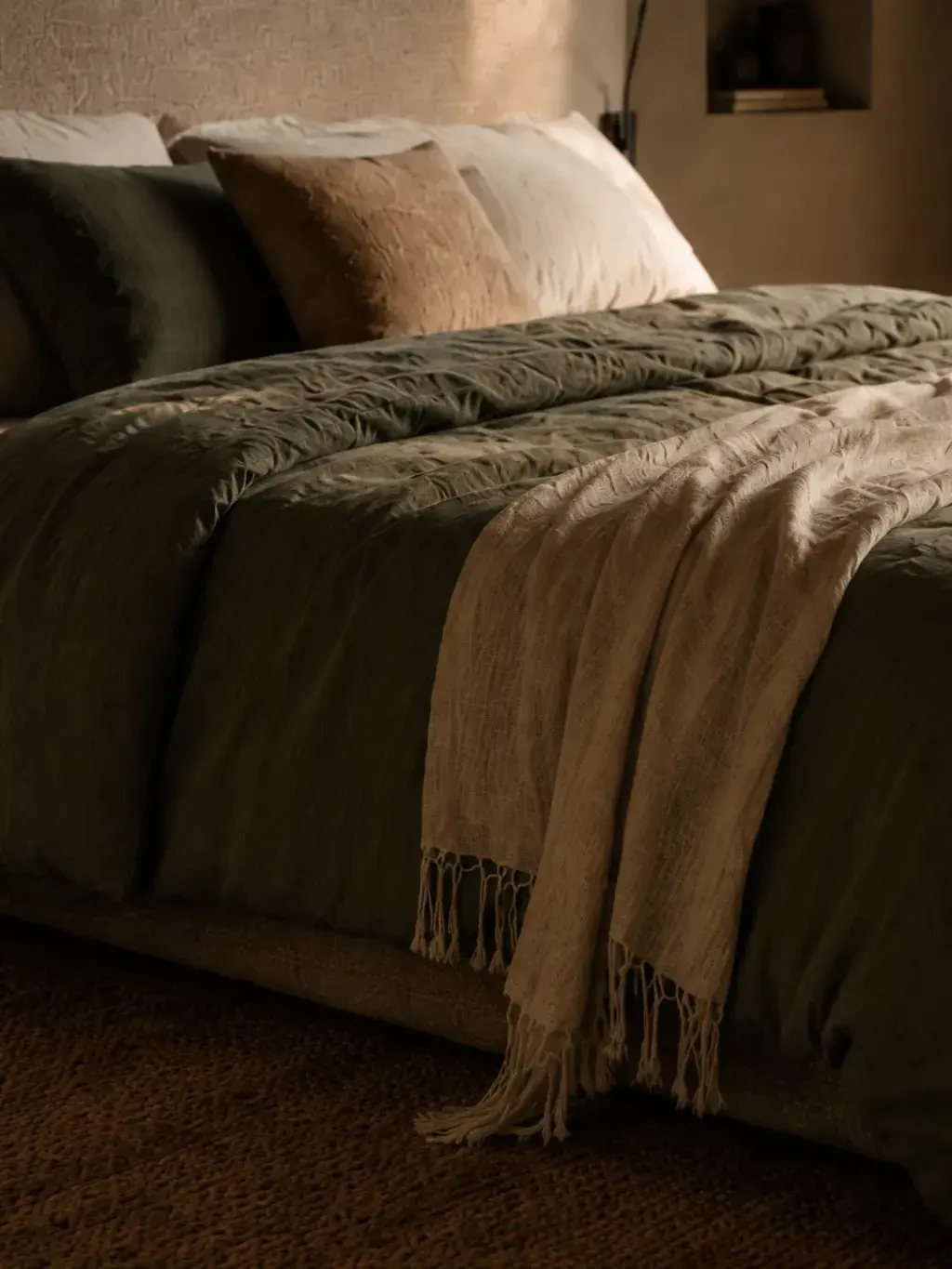 Lit avec draps en lin froissés aux tons naturels dans une chambre cosy
