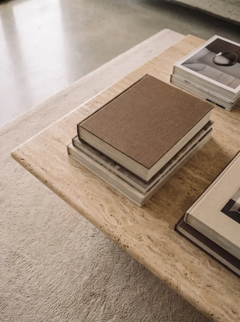 Livres empilés sur une table basse en travertin dans un intérieur moderne