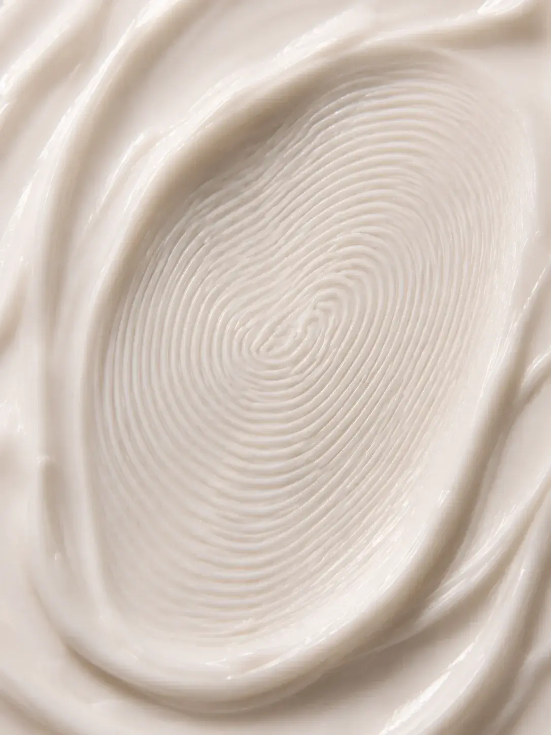 Macro extrême empreinte digitale en spirale dans crème blanche – sillons concentriques, texture soyeuse