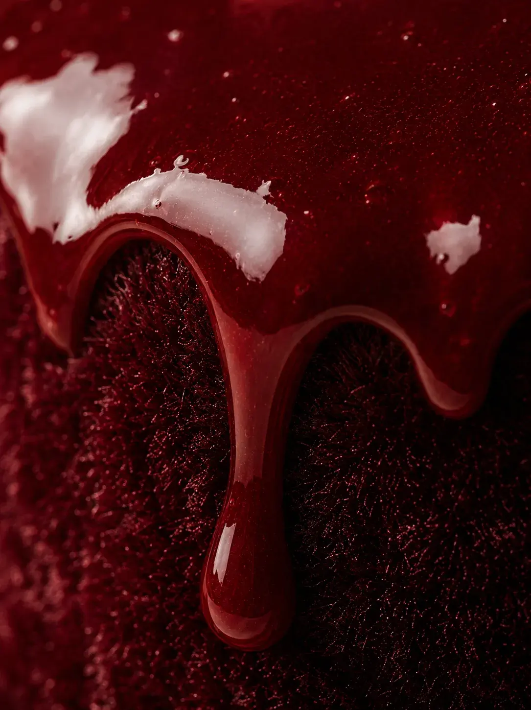 Macro glaçage miroir bordeaux coulant sur velours rouge – coulée profonde, teintes rubis sombres