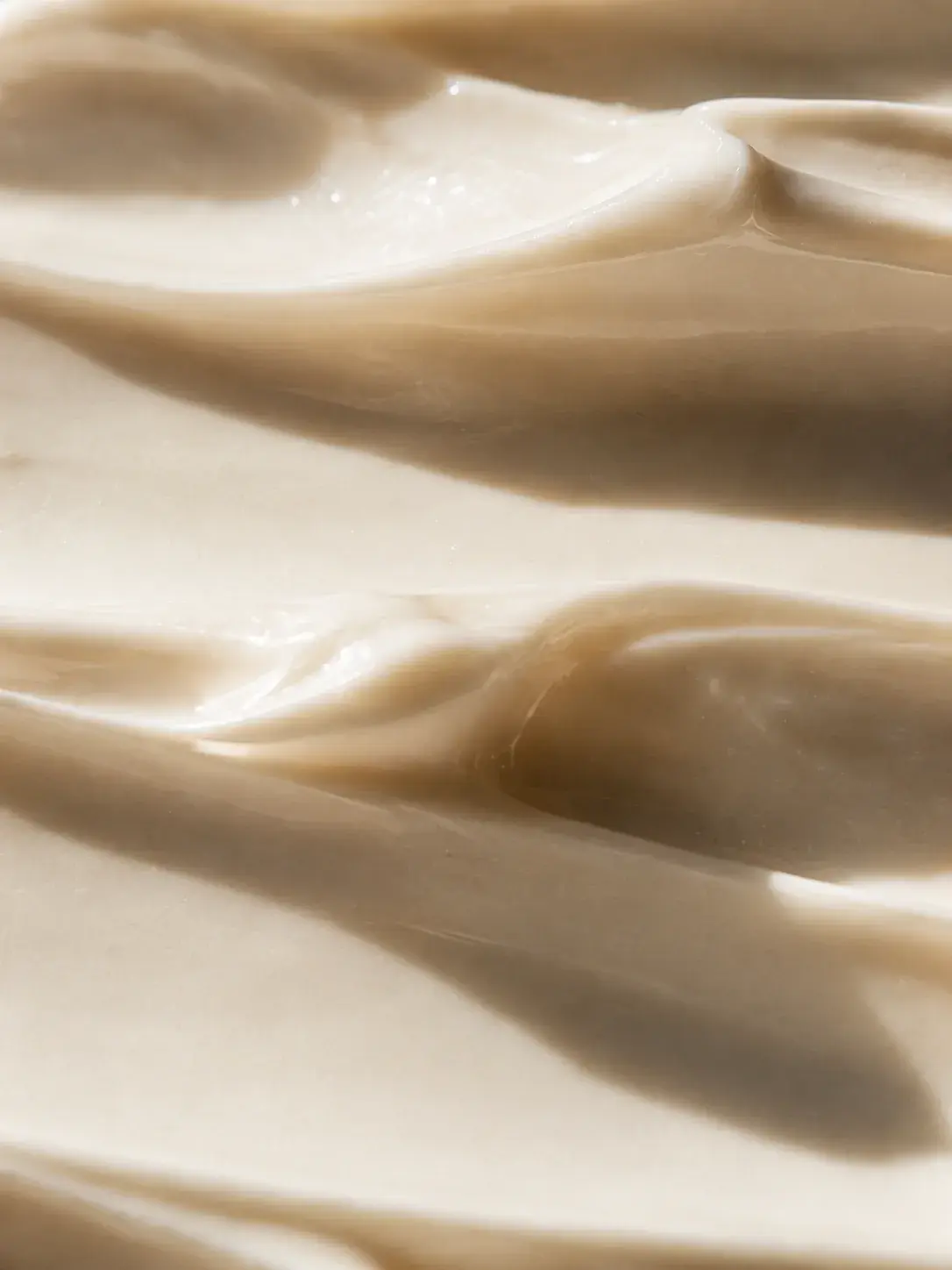 Macro texture crème en vagues beige crème – ondulations soyeuses, formule onctueuse, fond uni