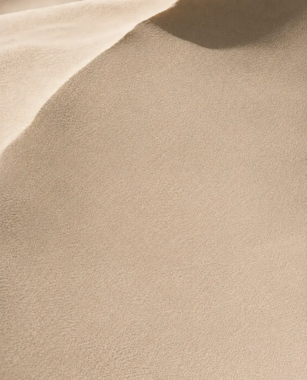 Macro texture de dune de sable fin – ondulations, courbes douces, lumière rasante, ombre