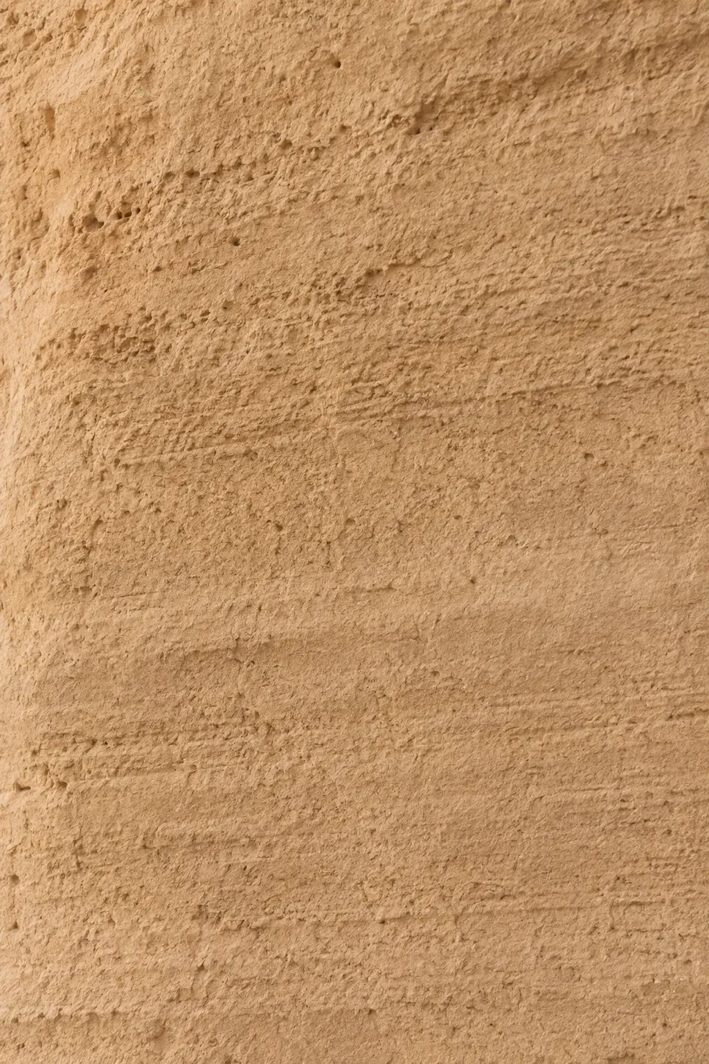 Macro texture mur de plâtre ocre sable – surface rugueuse, stries horizontales, fond neutre chaud