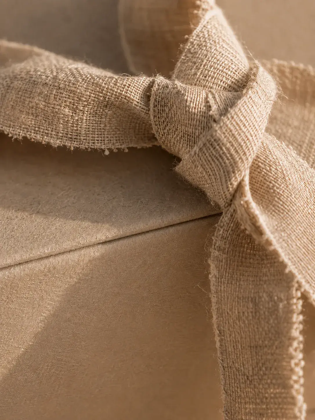 Macro tissu jute naturel noué sur fond kraft – texture fibre végétale brute, lumière chaude