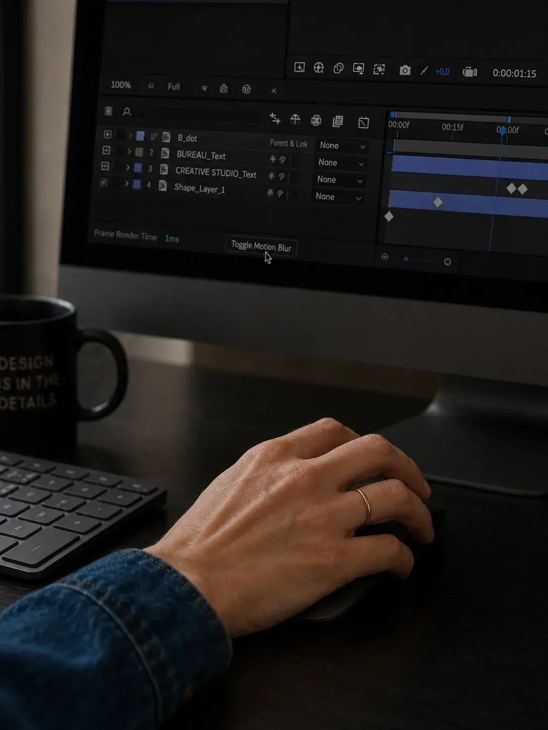 Main sur souris devant iMac avec timeline de montage vidéo et mug noir « Design is in the Details »