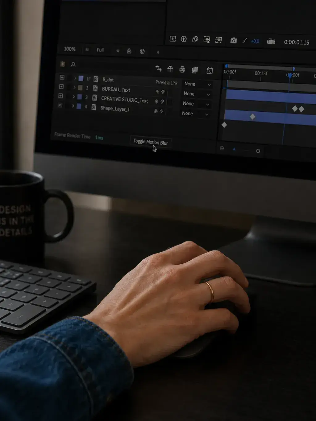Main sur souris devant iMac avec timeline de montage vidéo et mug noir « Design is in the Details »