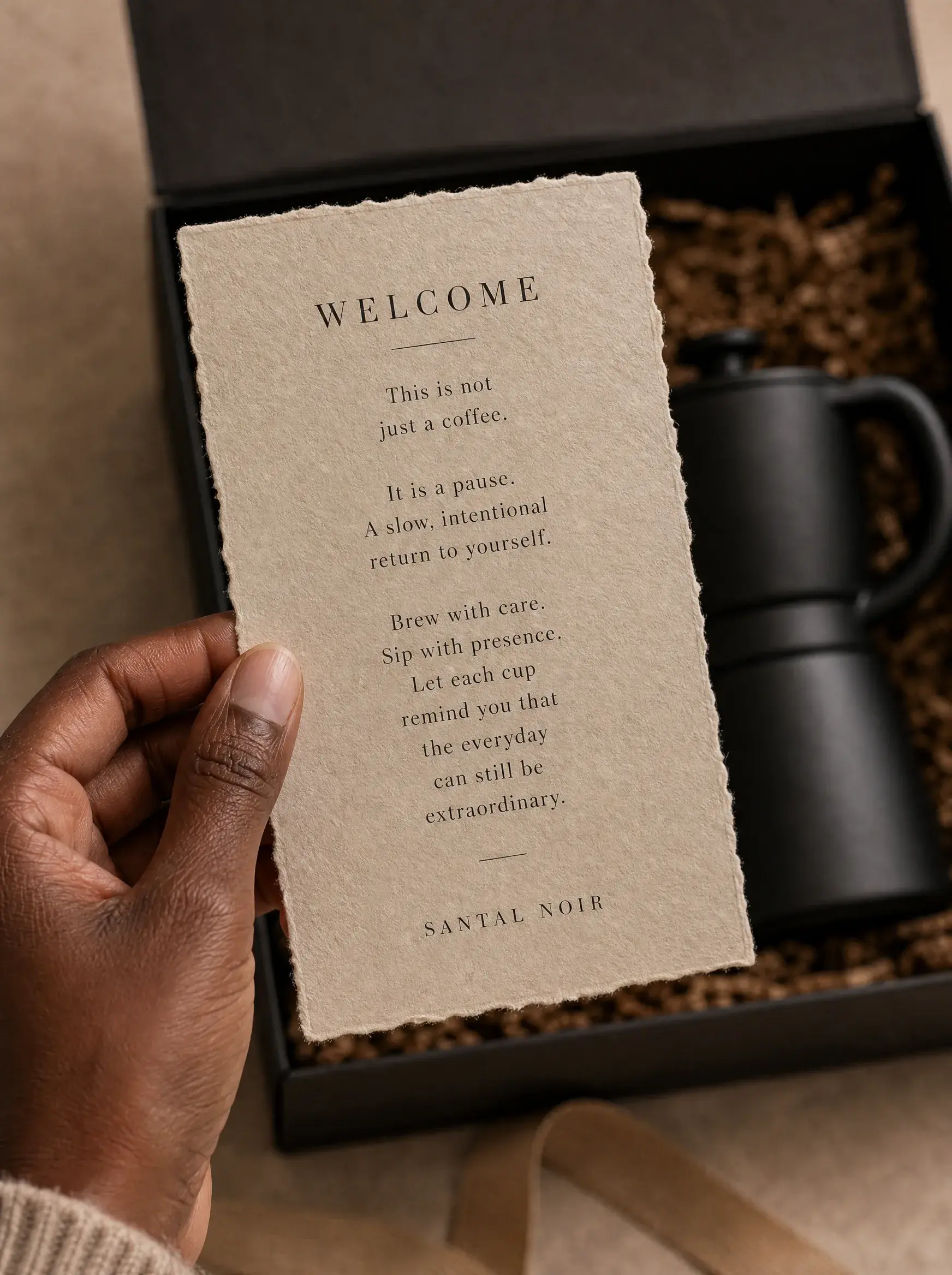 Main tenant carte bienvenue kraft dans coffret café – cafetière moka noire, paille décorative