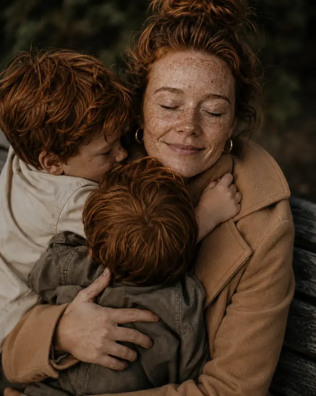 Mère aux taches de rousseur souriante étreignant deux enfants roux – extérieur automnal