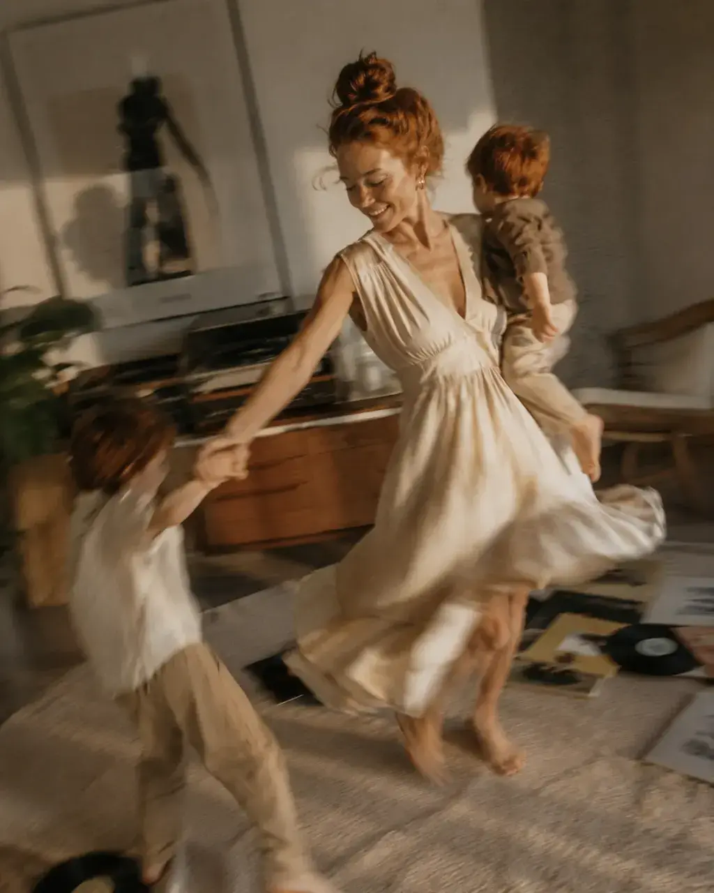 Mère en robe blanche dansant avec ses deux enfants roux – flou de mouvement et vinyles au sol
