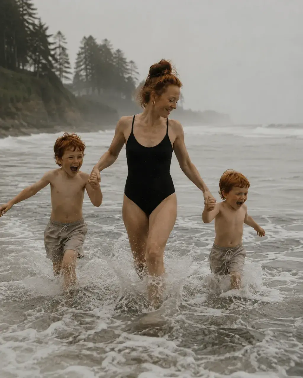Mère et fils courant dans les vagues sur une plage grise