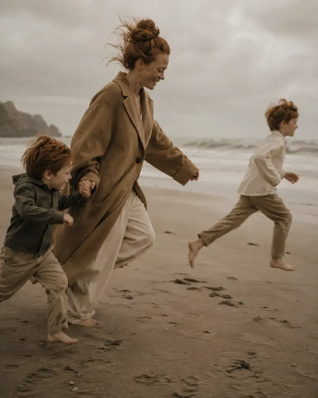 Mère et fils courant sur la plage par temps venteux
