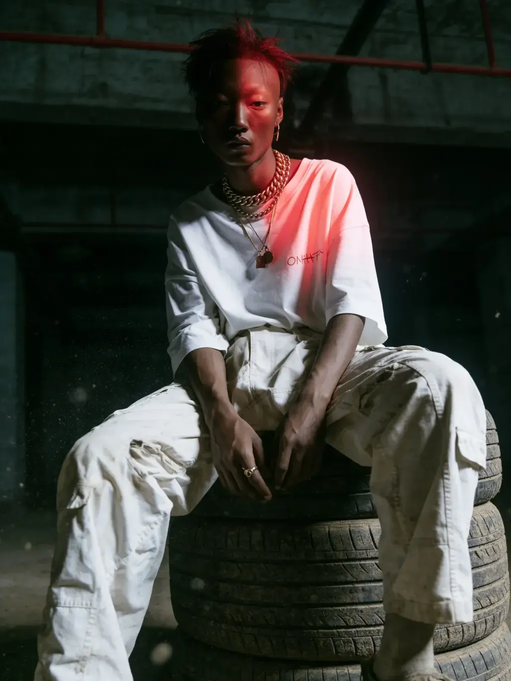Modèle aux cheveux rouges sur des pneus éclairé d'un faisceau rouge vif en t-shirt OLAH-H