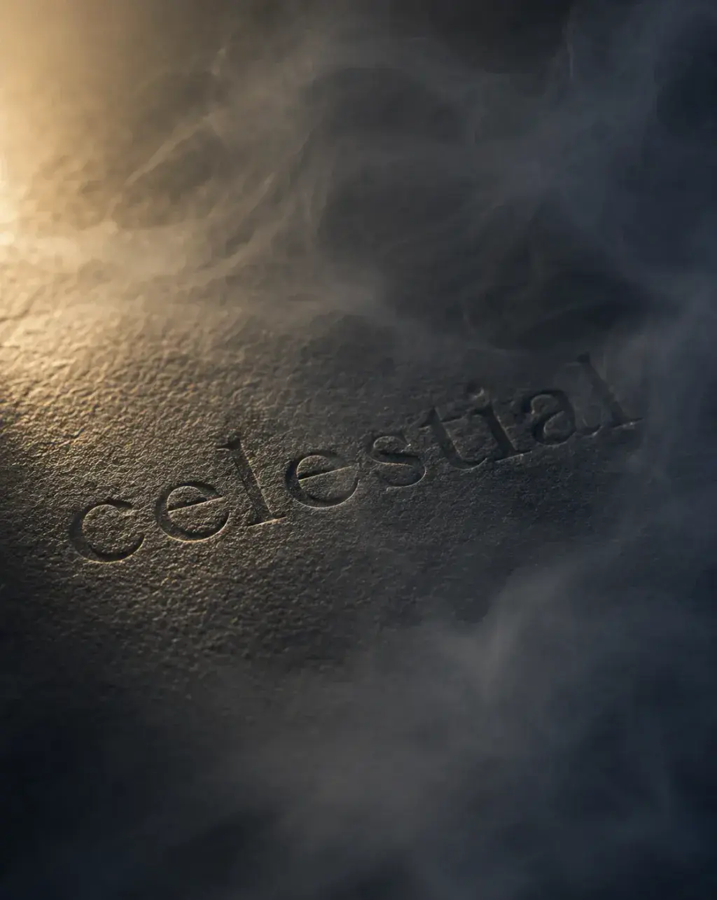 Mot « celestial » gravé en relief sur surface texturée sombre avec lumière rasante dorée et voile de fumée translucide