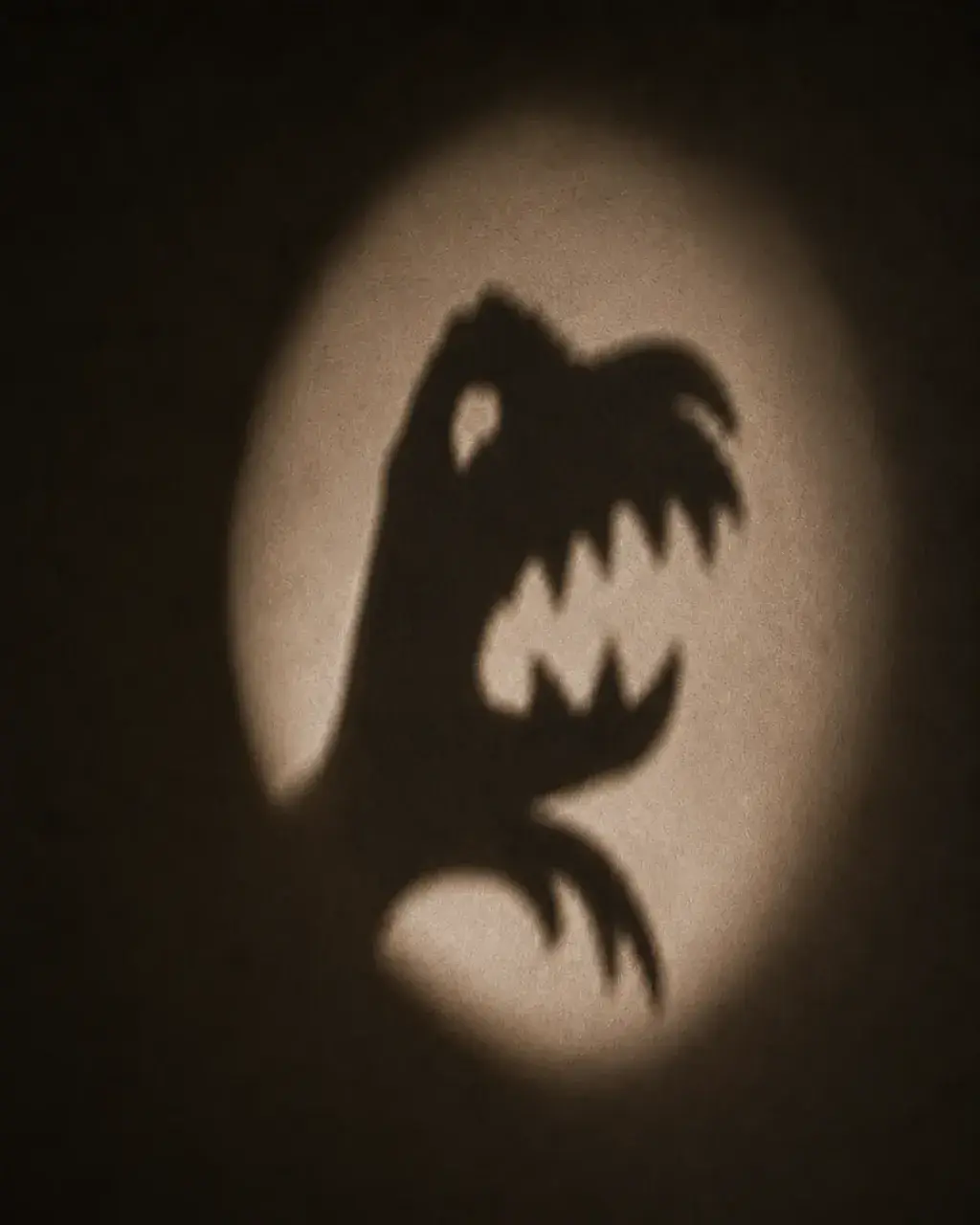 Ombre chinoise d'un monstre sur un mur éclairé par lampe torche – jeu de lumière nocturne