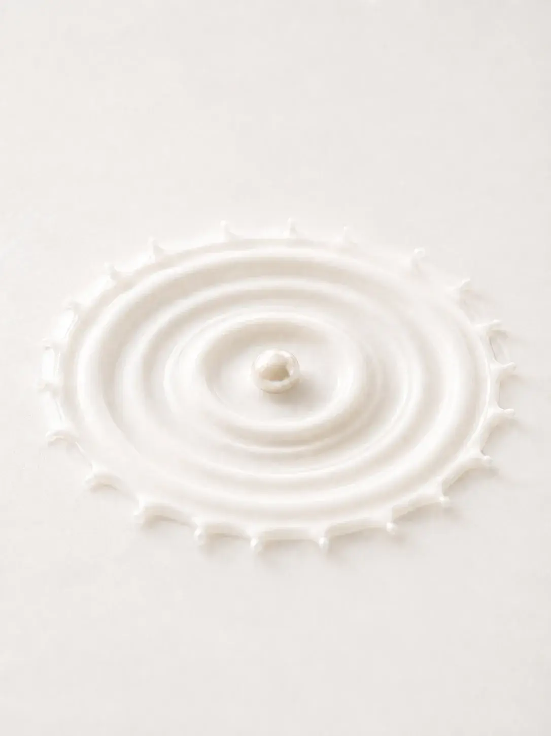 Perle unique au cœur d'une couronne d'éclaboussure de crème blanche aux bords dentelés