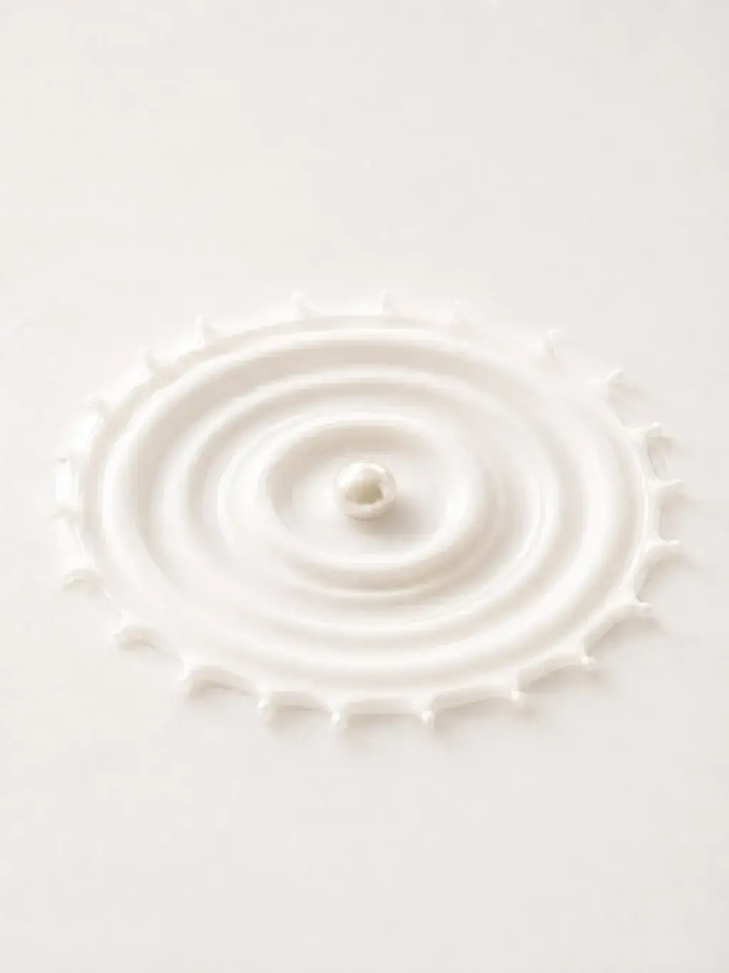 Perle unique au cœur d'une couronne d'éclaboussure de crème blanche aux bords dentelés