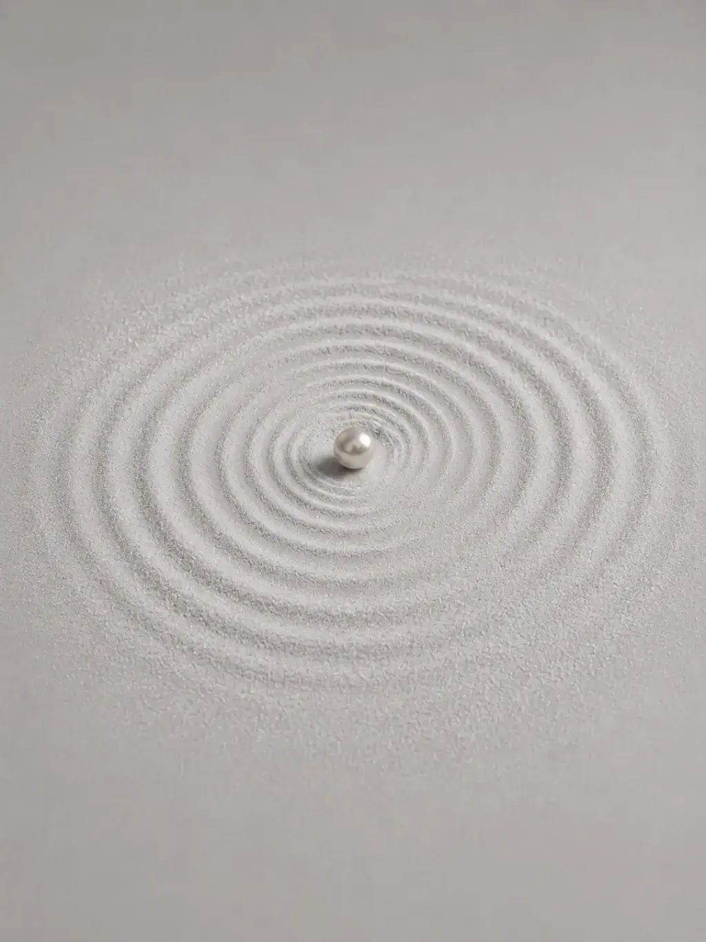 Perle unique au centre de cercles concentriques tracés dans le sable blanc, jardin zen