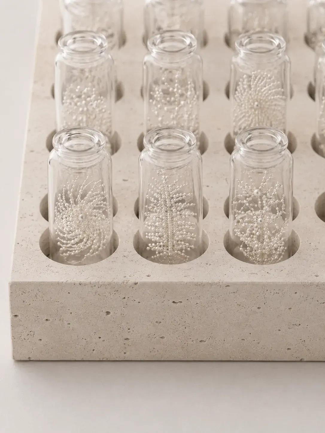 Plateau en travertin avec flacons de verre renfermant des motifs nacrés en flocons, collection d'échantillons