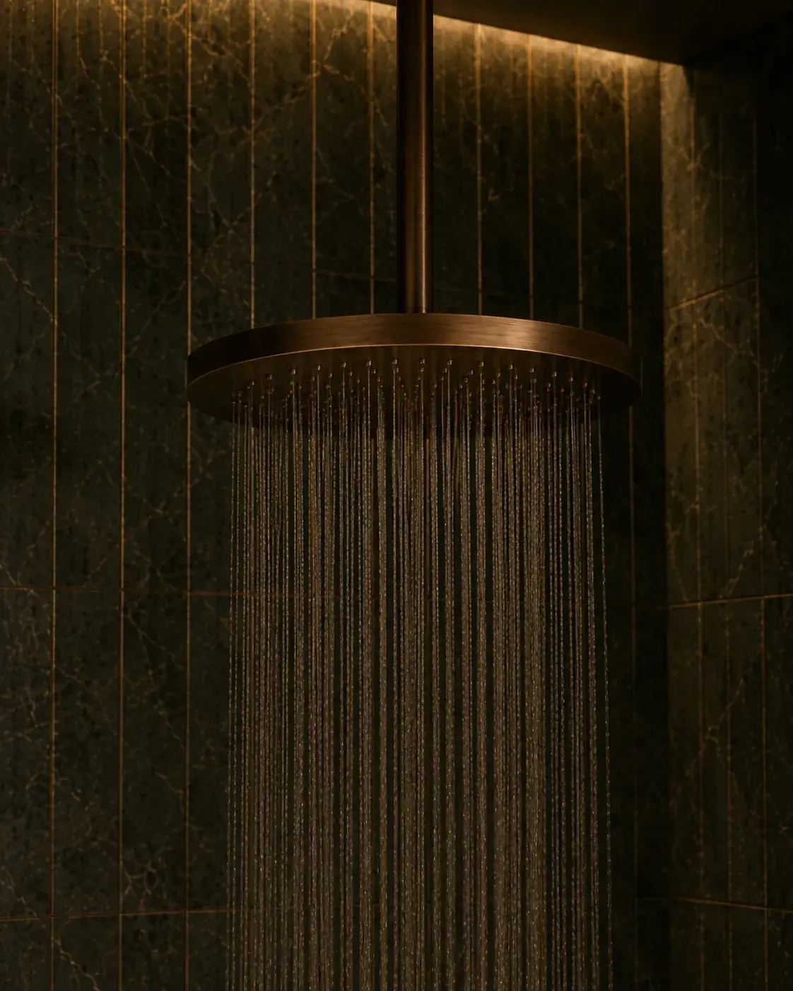 Pommeau de douche à effet pluie en cuivre ou laiton brossé dans une douche sombre