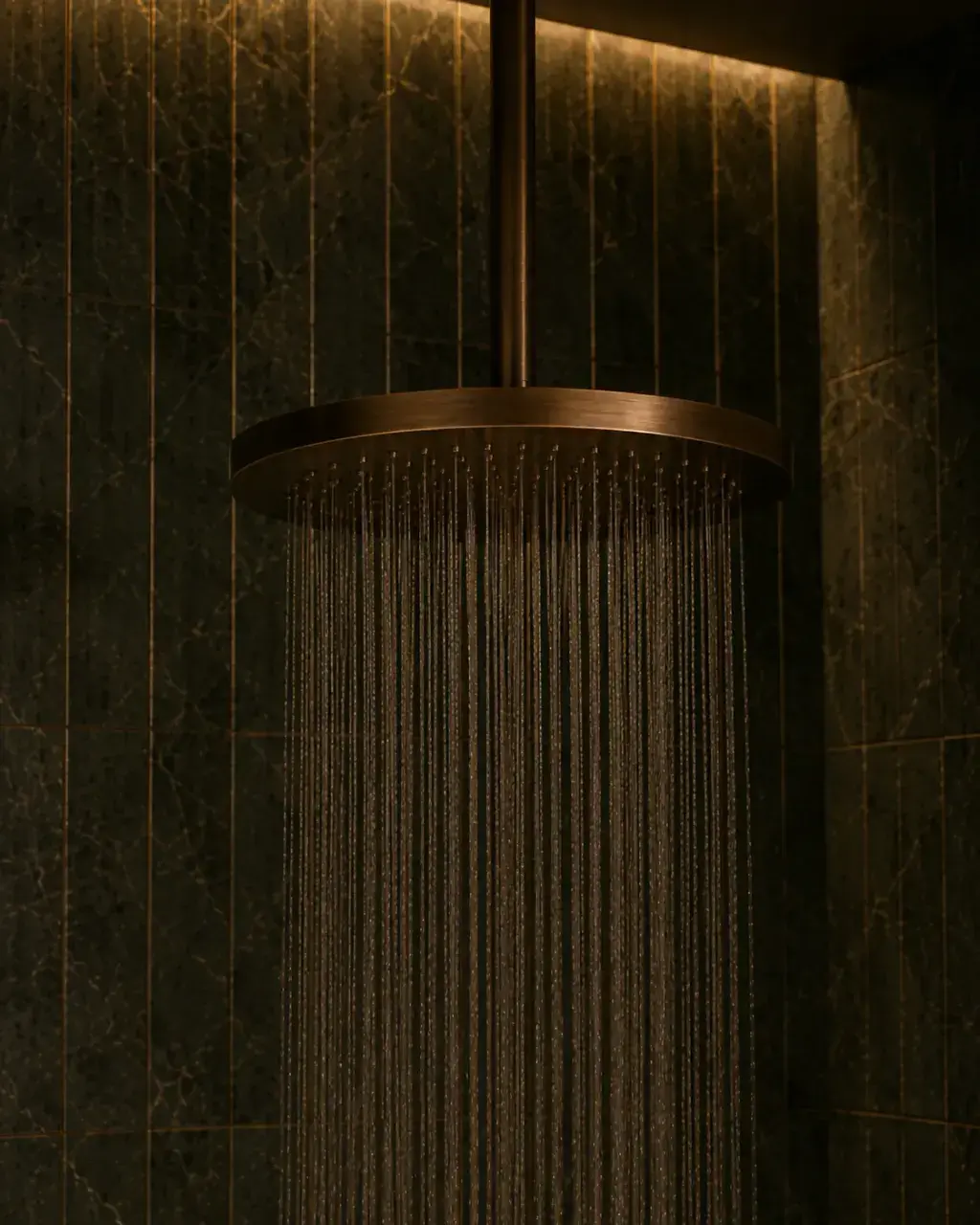Pommeau de douche à effet pluie en cuivre ou laiton brossé dans une douche sombre