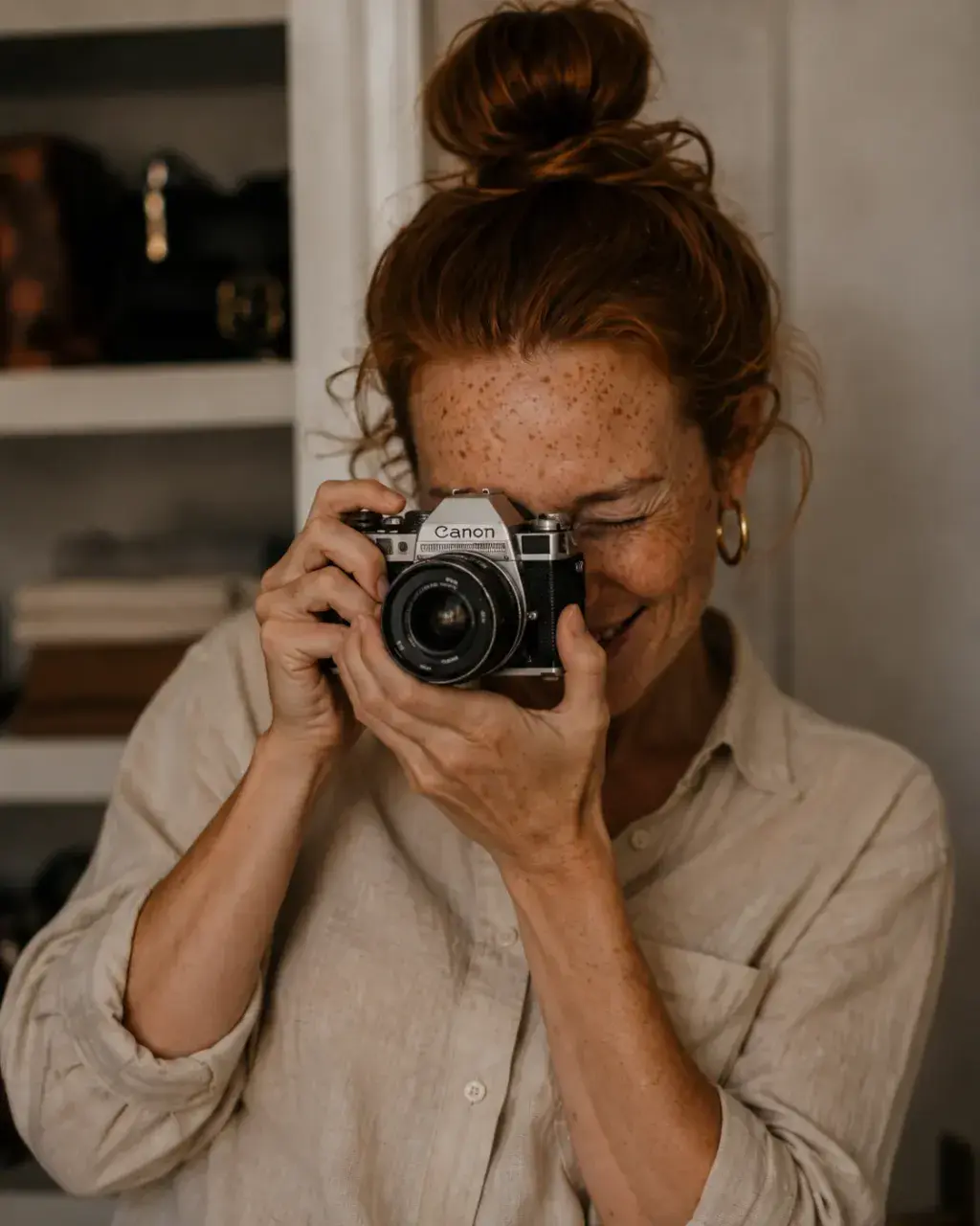 Portrait de femme rousse avec un appareil Canon argentique