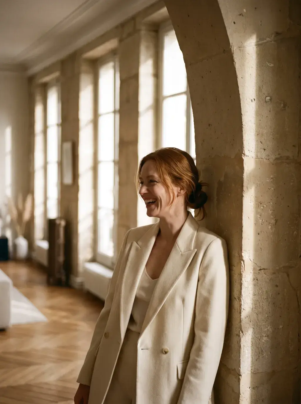 Portrait de femme rousse en blazer blanc contre une arcade en pierre