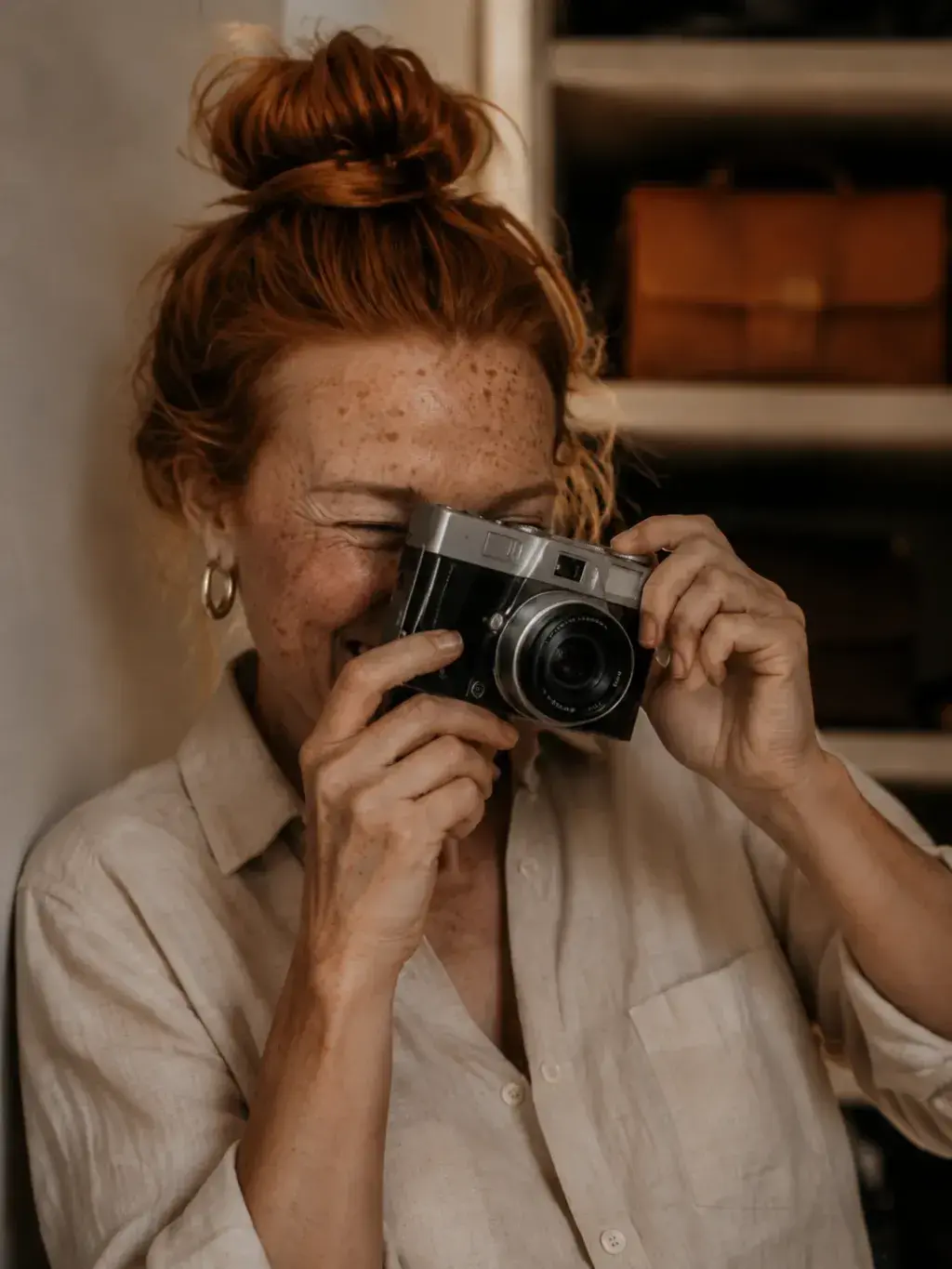 Portrait de femme rousse photographiant avec un appareil argentique