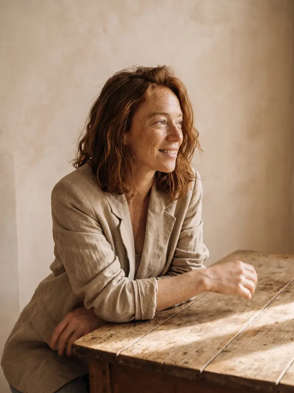 Portrait de femme rousse souriante accoudée à une table rustique