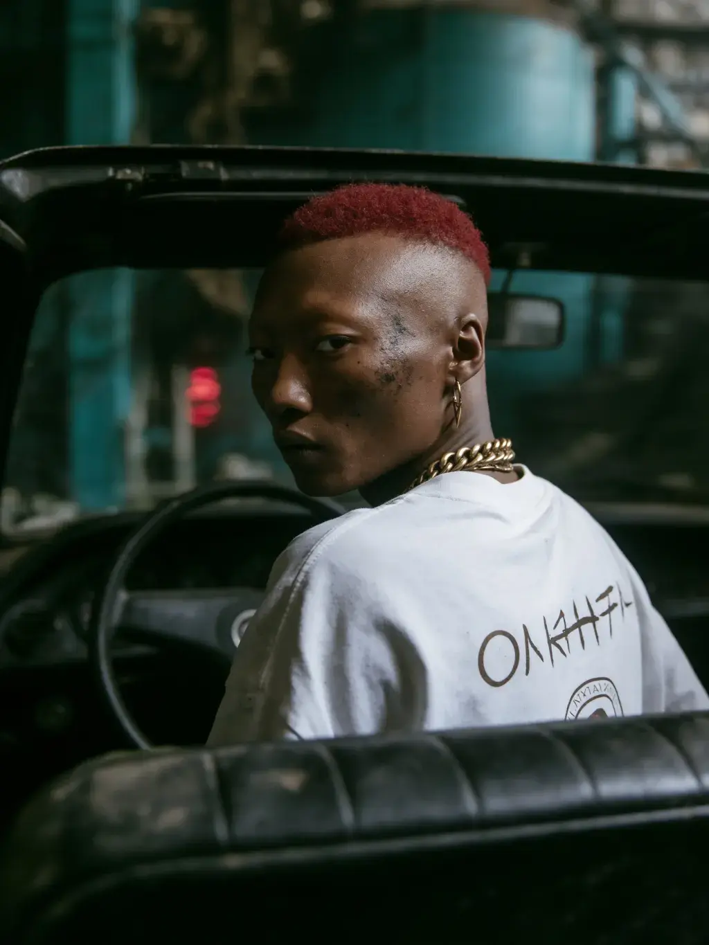 Portrait du modèle OLAH-H assis dans un vieux véhicule vintage avec regard de côté pensif