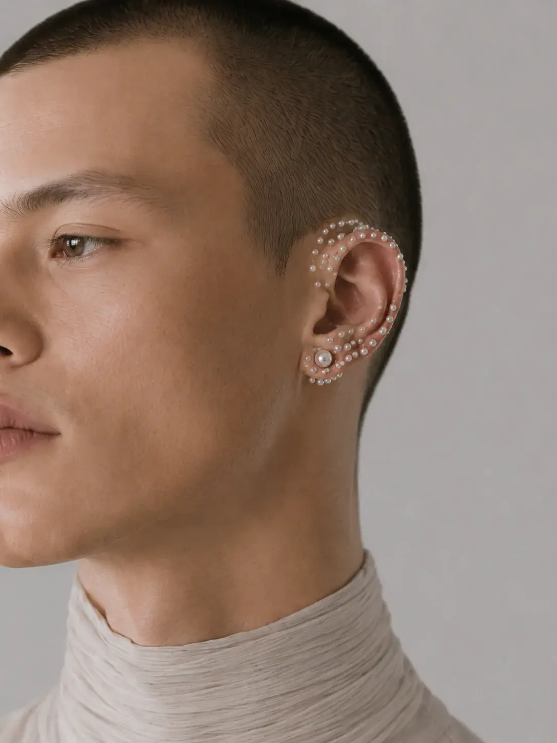 Portrait masculin de profil, multiples ear cuffs en perles autour de l'oreille, bijou éditorial