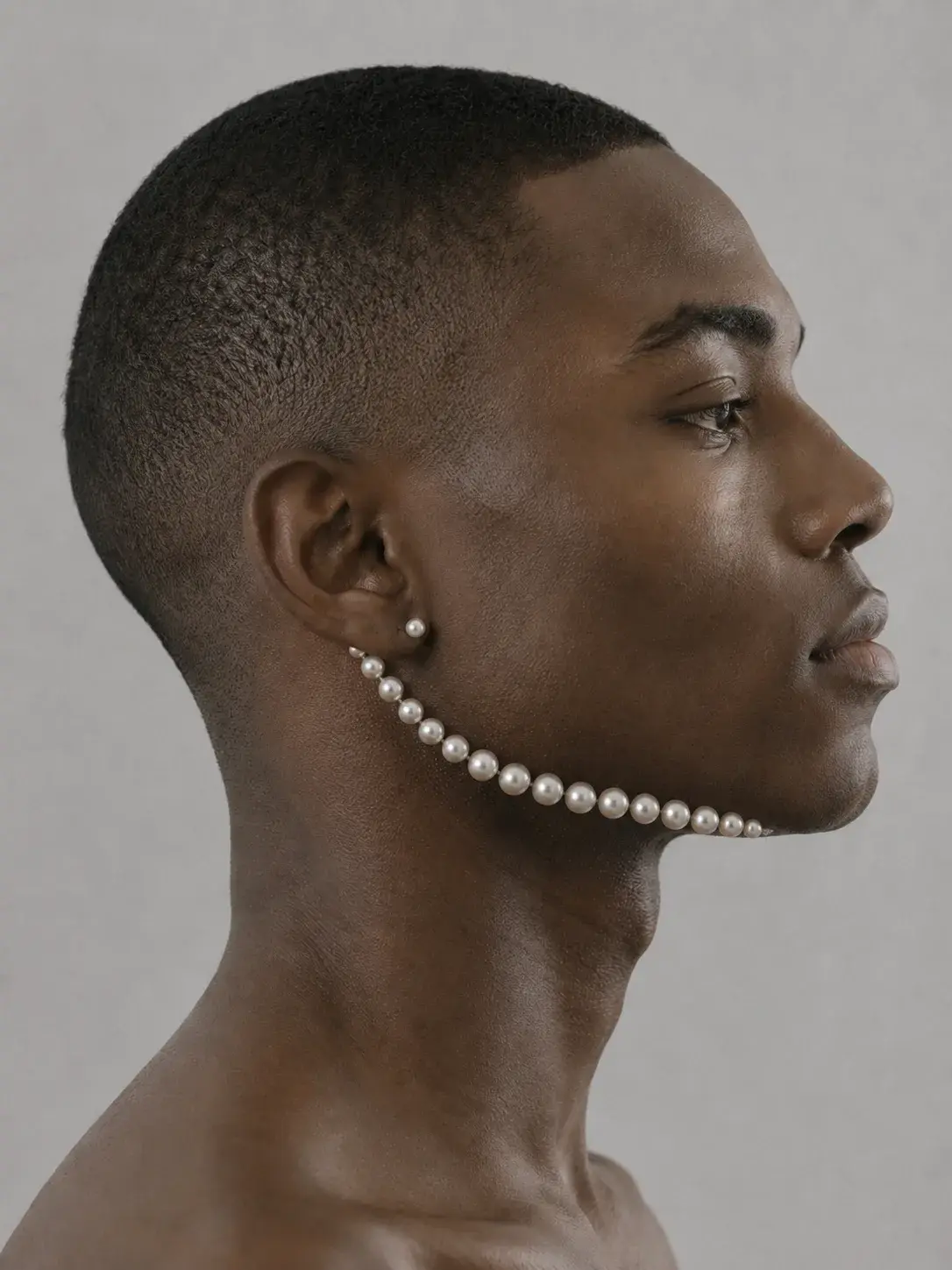 Portrait masculin de profil, rang de perles courant de l'oreille à la mâchoire comme un bijou ancré