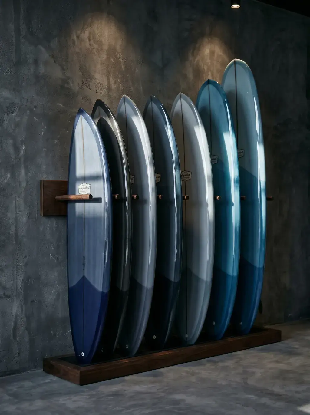 Rangée de planches de surf multicolores sur rack en bois contre un mur gris