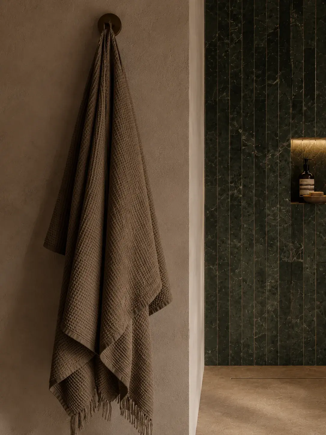 Serviette en lin lavé gris anthracite suspendue à une patère murale à côté d'une douche