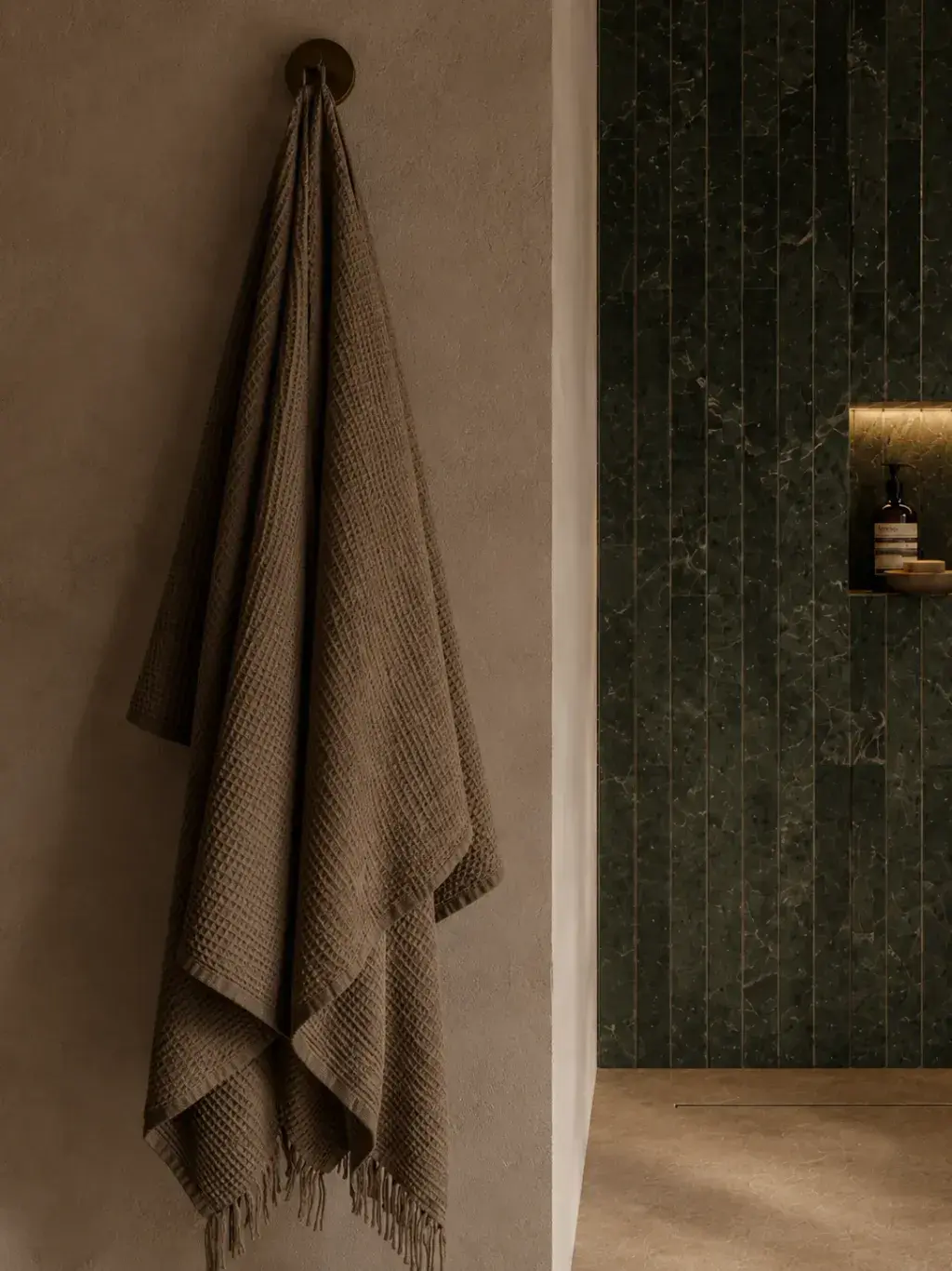Serviette en lin lavé gris anthracite suspendue à une patère murale à côté d'une douche