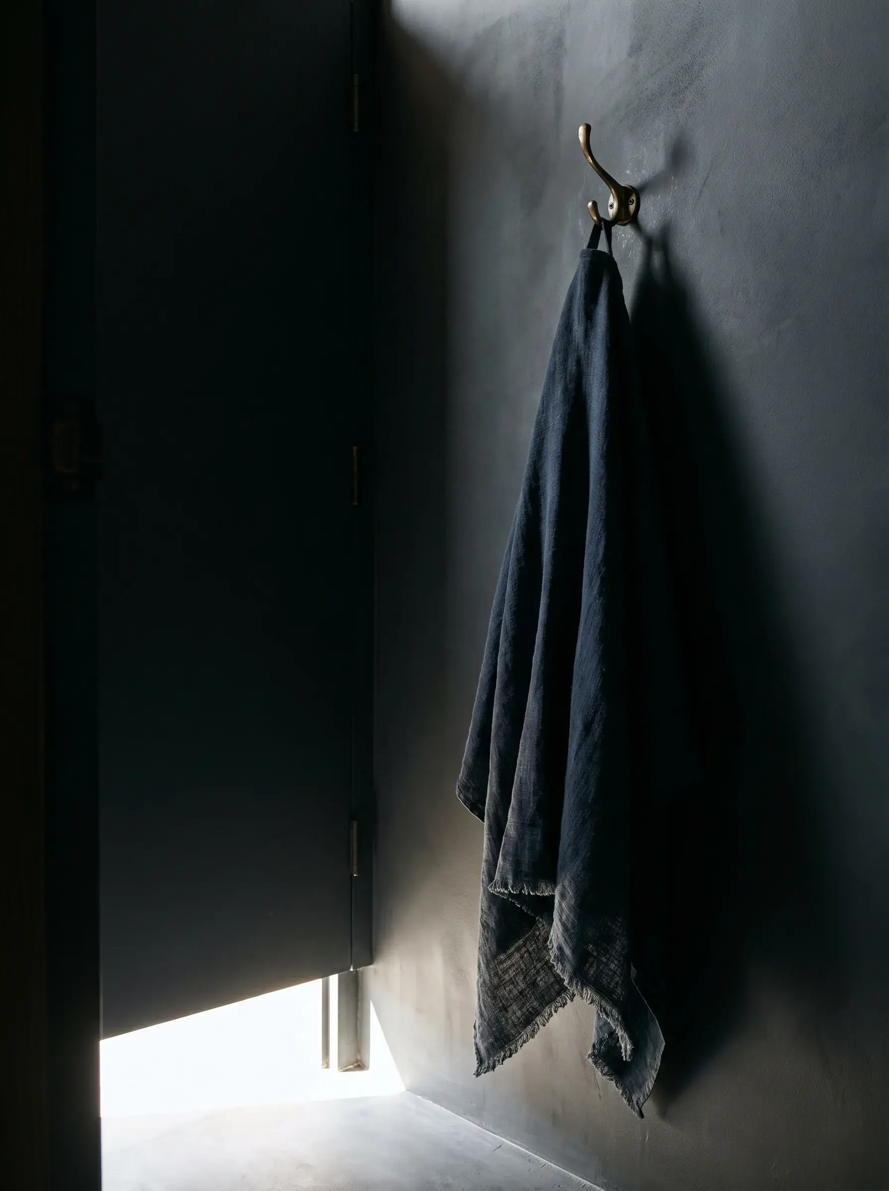 Serviette en lin marine accrochée à un crochet sur mur sombre