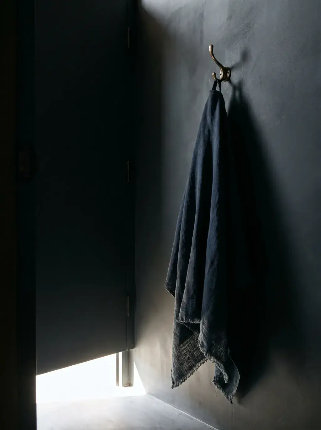 Serviette en lin marine accrochée à un crochet sur mur sombre