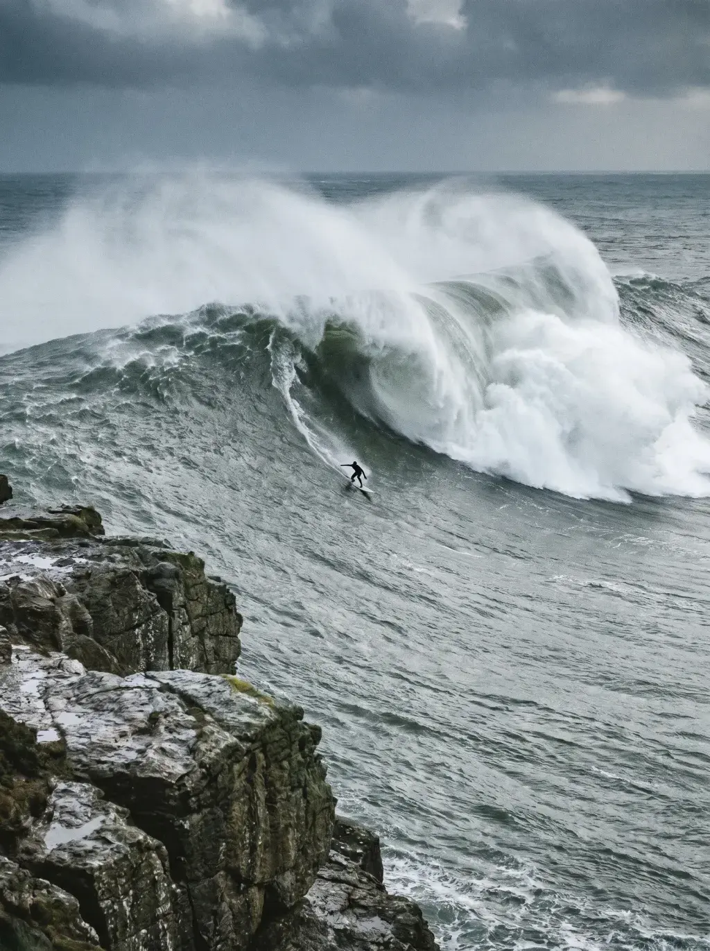 Surfeur descendant une énorme vague sous un ciel d'orage
