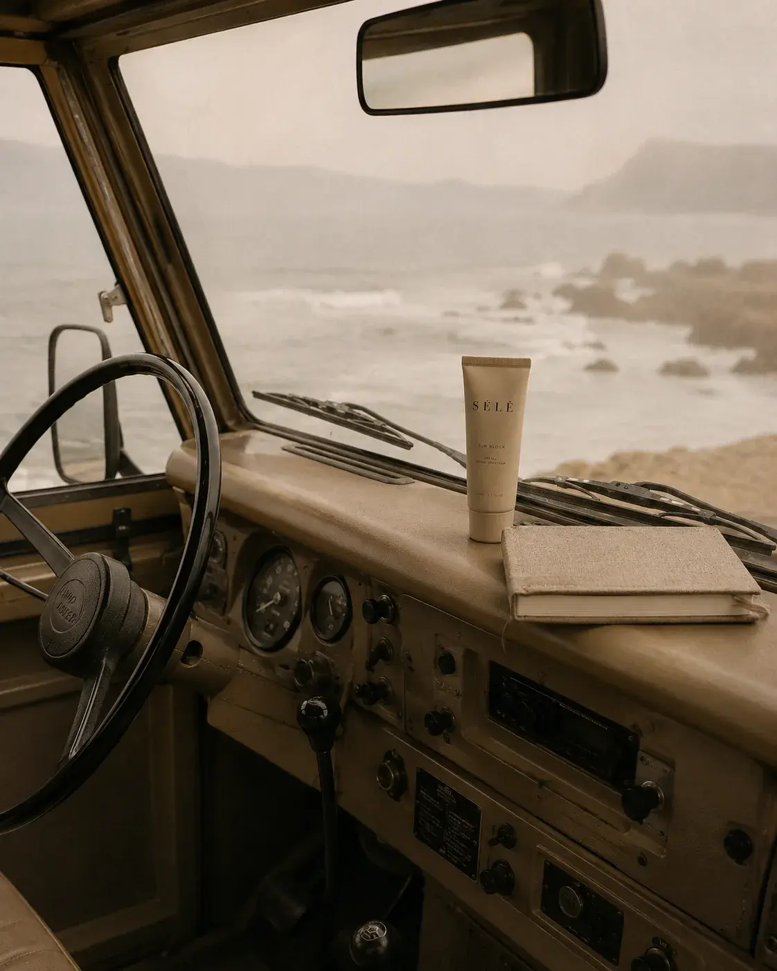 Tableau de bord 4x4 vintage – tube crème solaire sur carnet, mer agitée par le pare-brise, road trip
