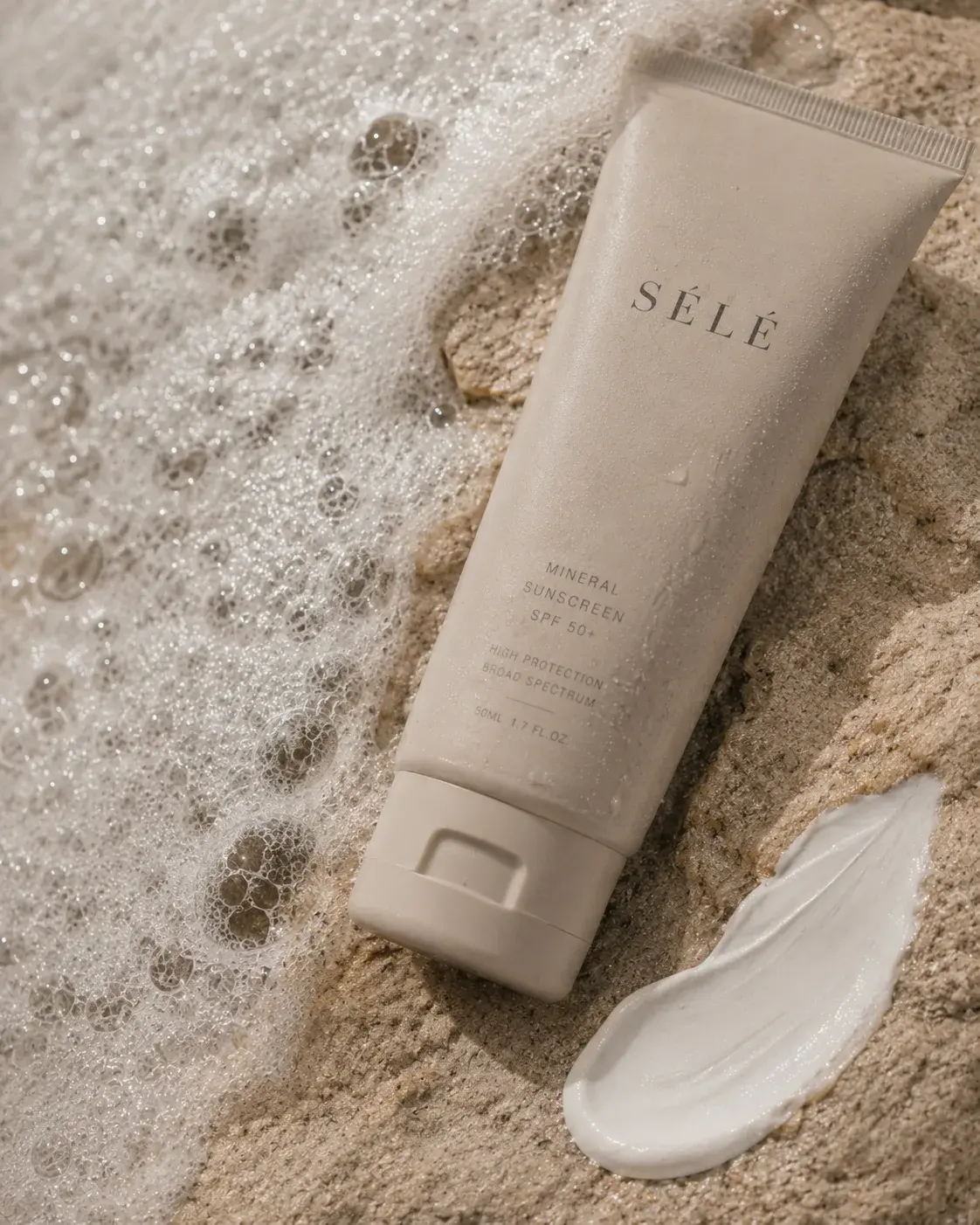 Tube crème solaire minérale sur sable mouillé avec écume – trace de crème, vague, plage, lumière
