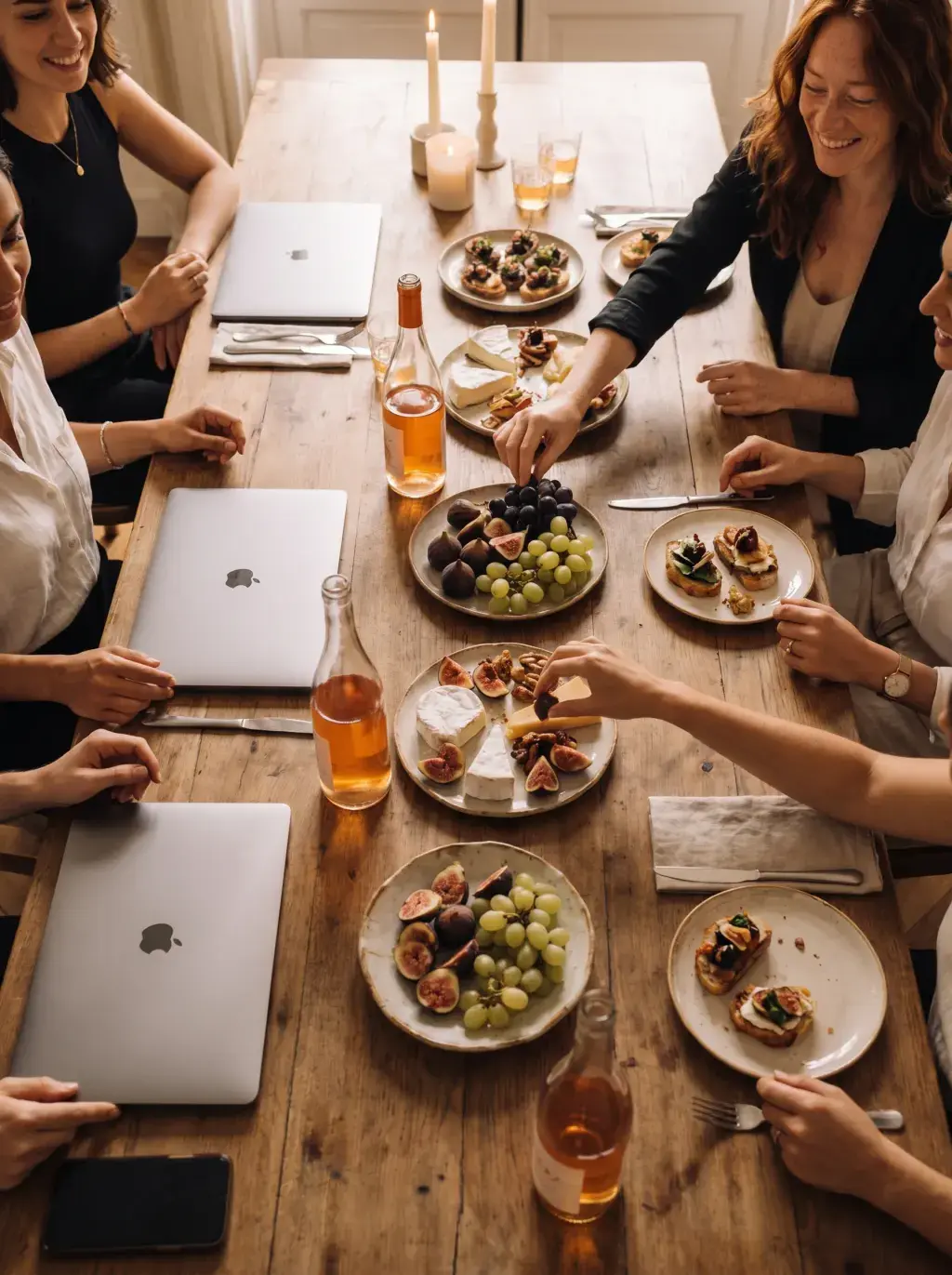 Vue aérienne d'un dîner de travail festif avec charcuteries, figues et laptops sur grande table