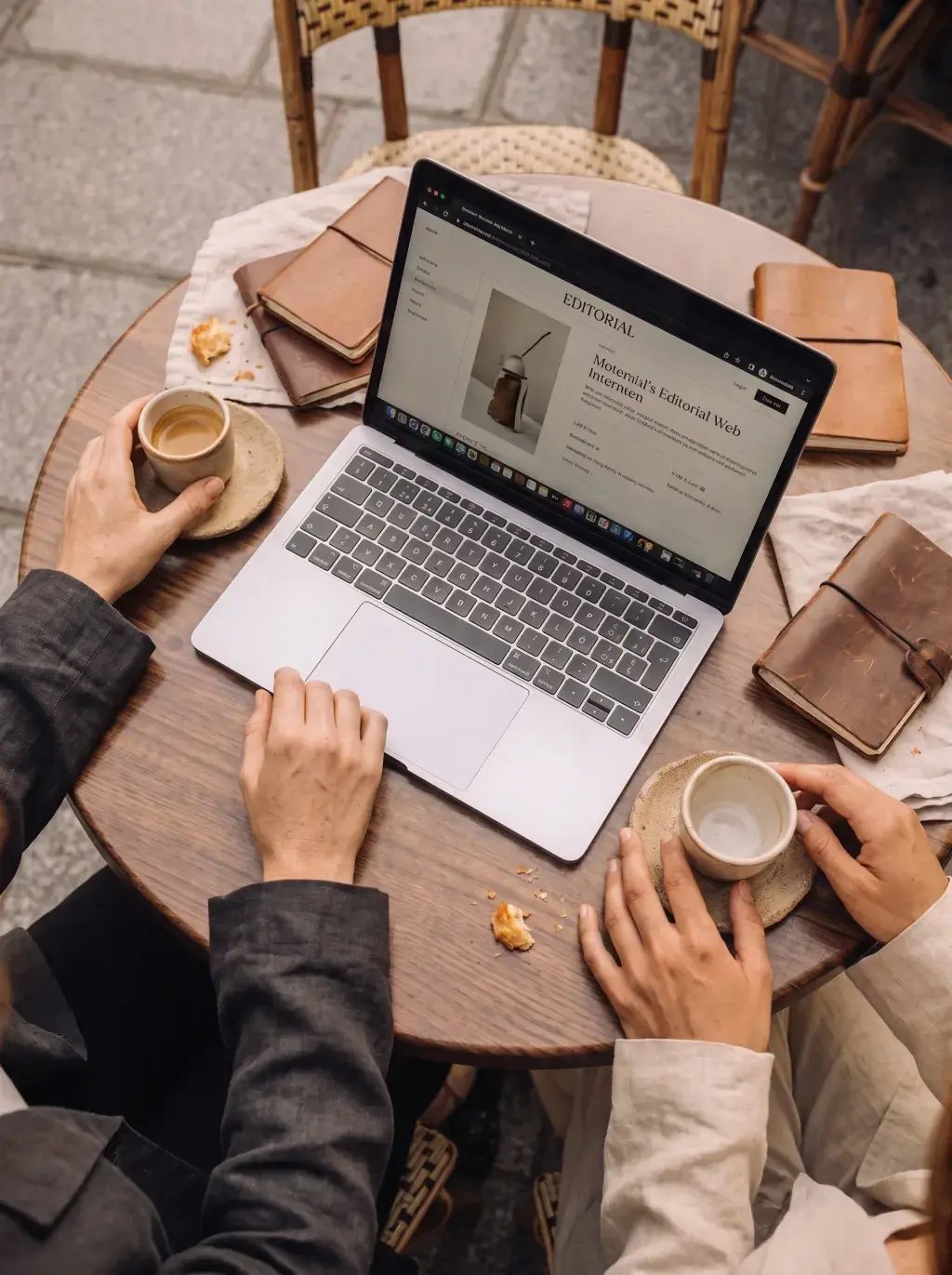 Vue aérienne de deux personnes travaillant sur un laptop en terrasse avec café et carnets