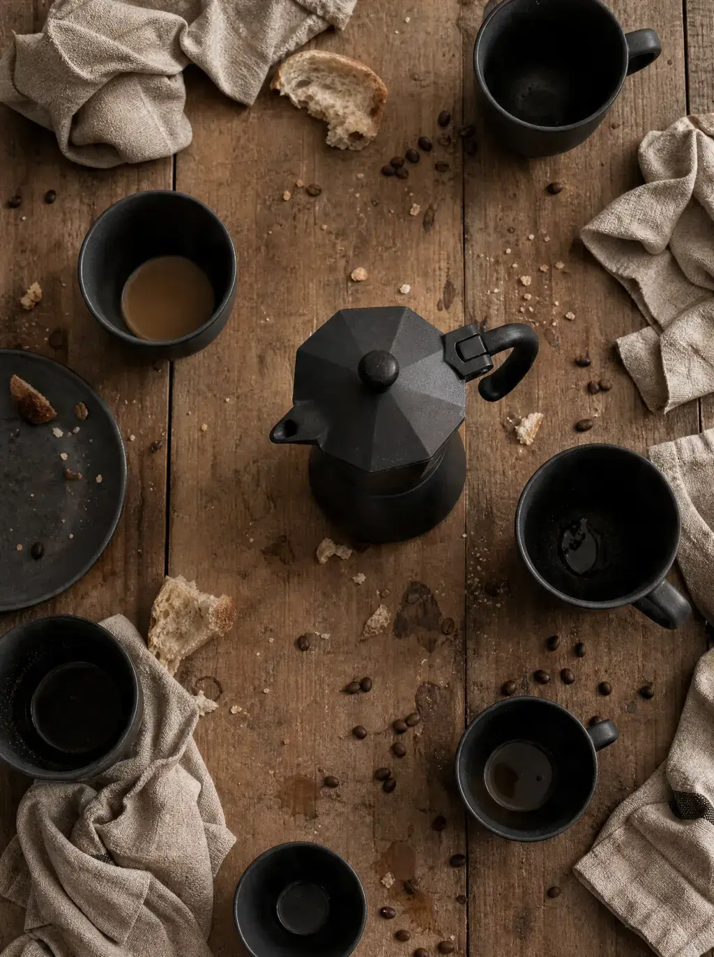 Vue de dessus – cafetière moka, six mugs noirs, pain, nappe lin, table bois – rassemblement convivial