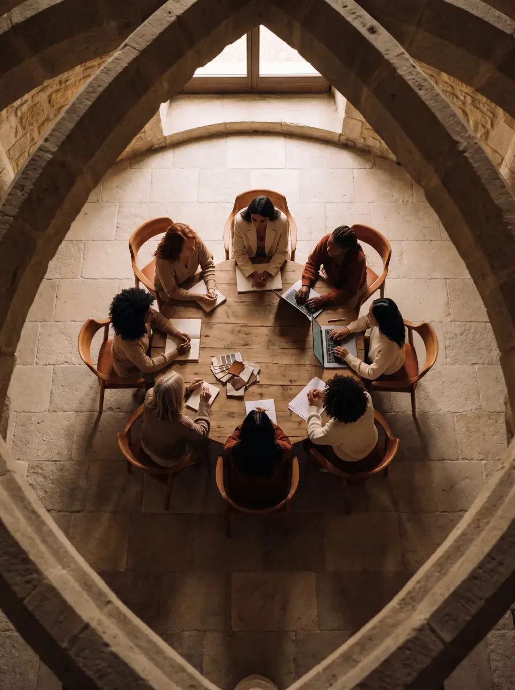 Vue de dessus d'une réunion créative sous des arches en pierre avec nuanciers et laptop